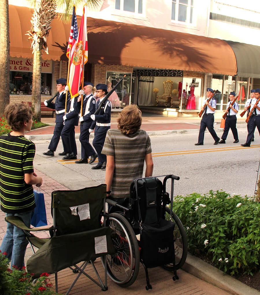 photo of high school teen trying to stand for the flag from a conventional wheelchair