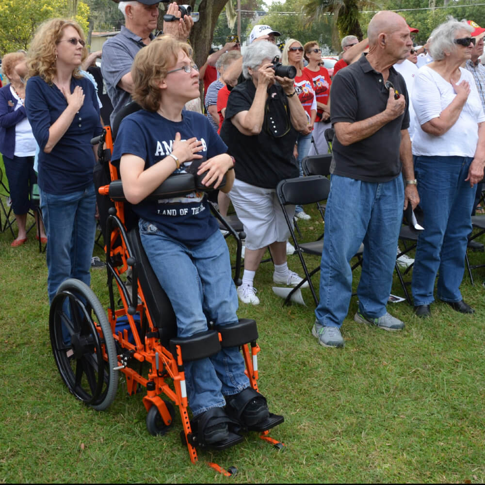 Arek Trenholm stands for the pledge of allegiance in his manual power standing wheelchair